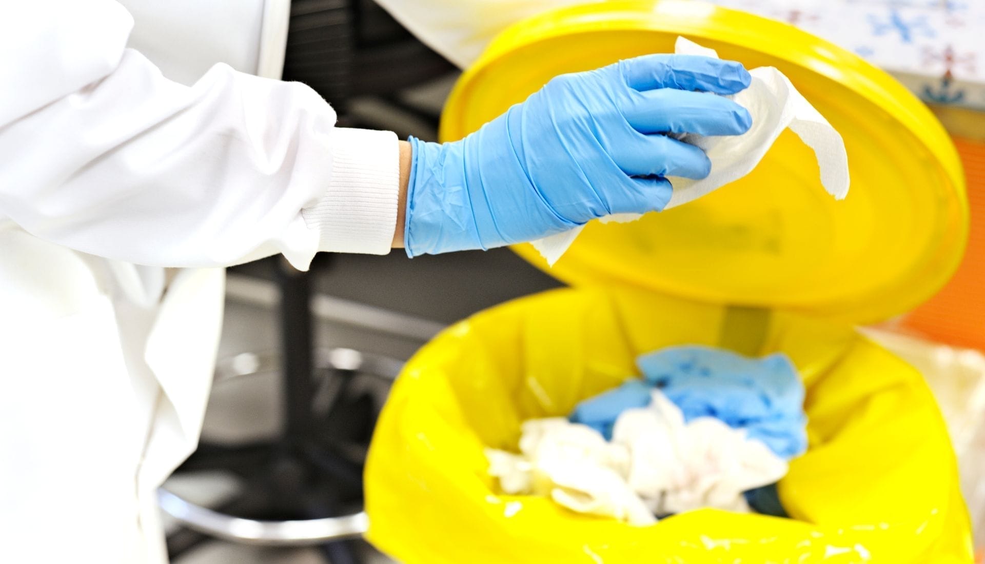 Lab worker disposing waste in yellow bin