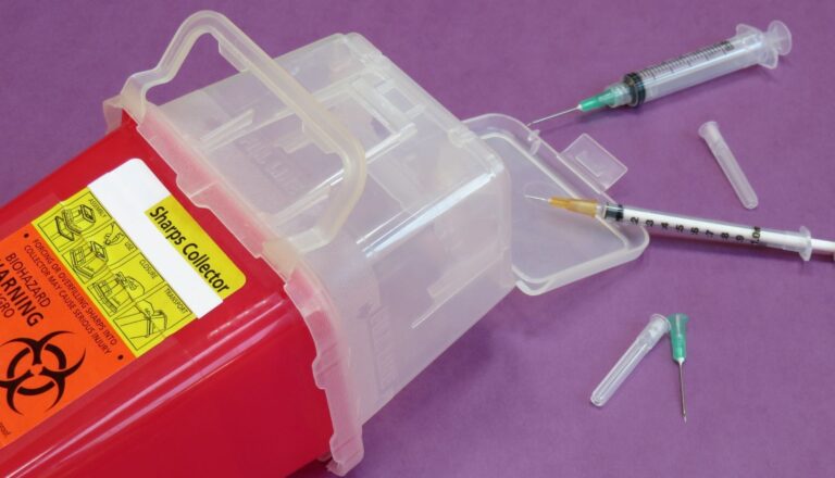 Biohazard sharps container with syringe and needle