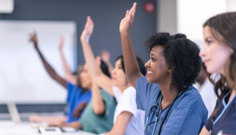 Medical students raising hands in classroom