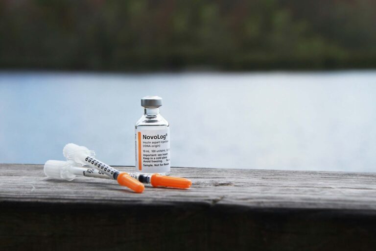 Insulin bottle and syringes by the water.