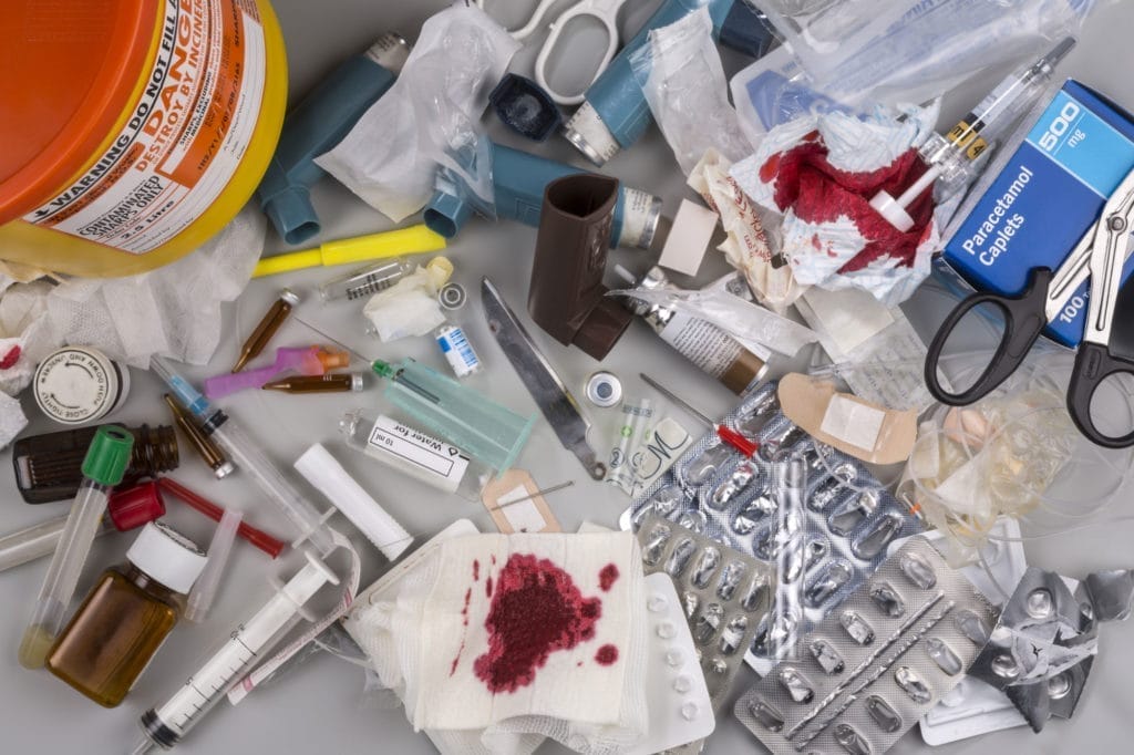 Used medical supplies and medication waste on table.
