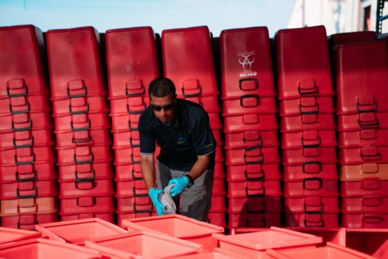 Worker handling red bins outdoors