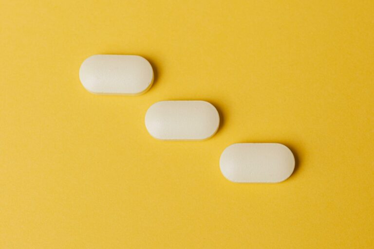Three white pills on yellow background
