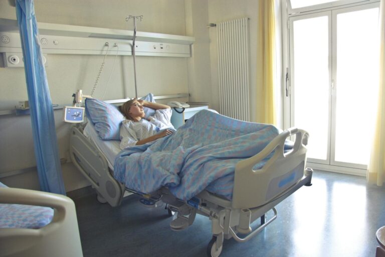 Patient resting in hospital bed by window.