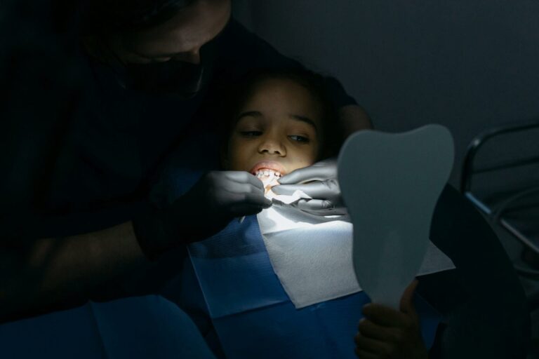 Dentist examining child's teeth with mirror.