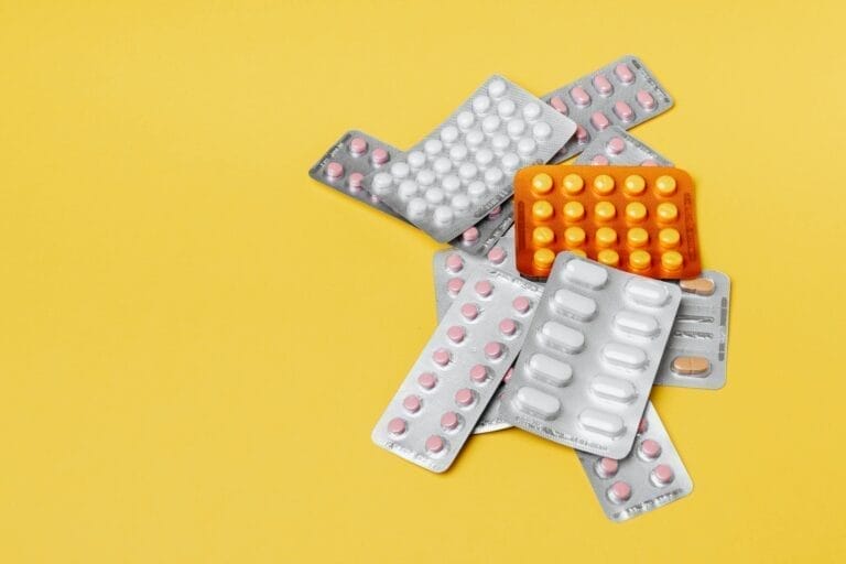 Assorted blister packs of pills on yellow background.