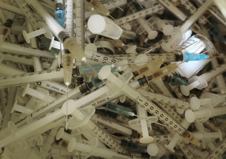 Pile of used medical syringes and needles.