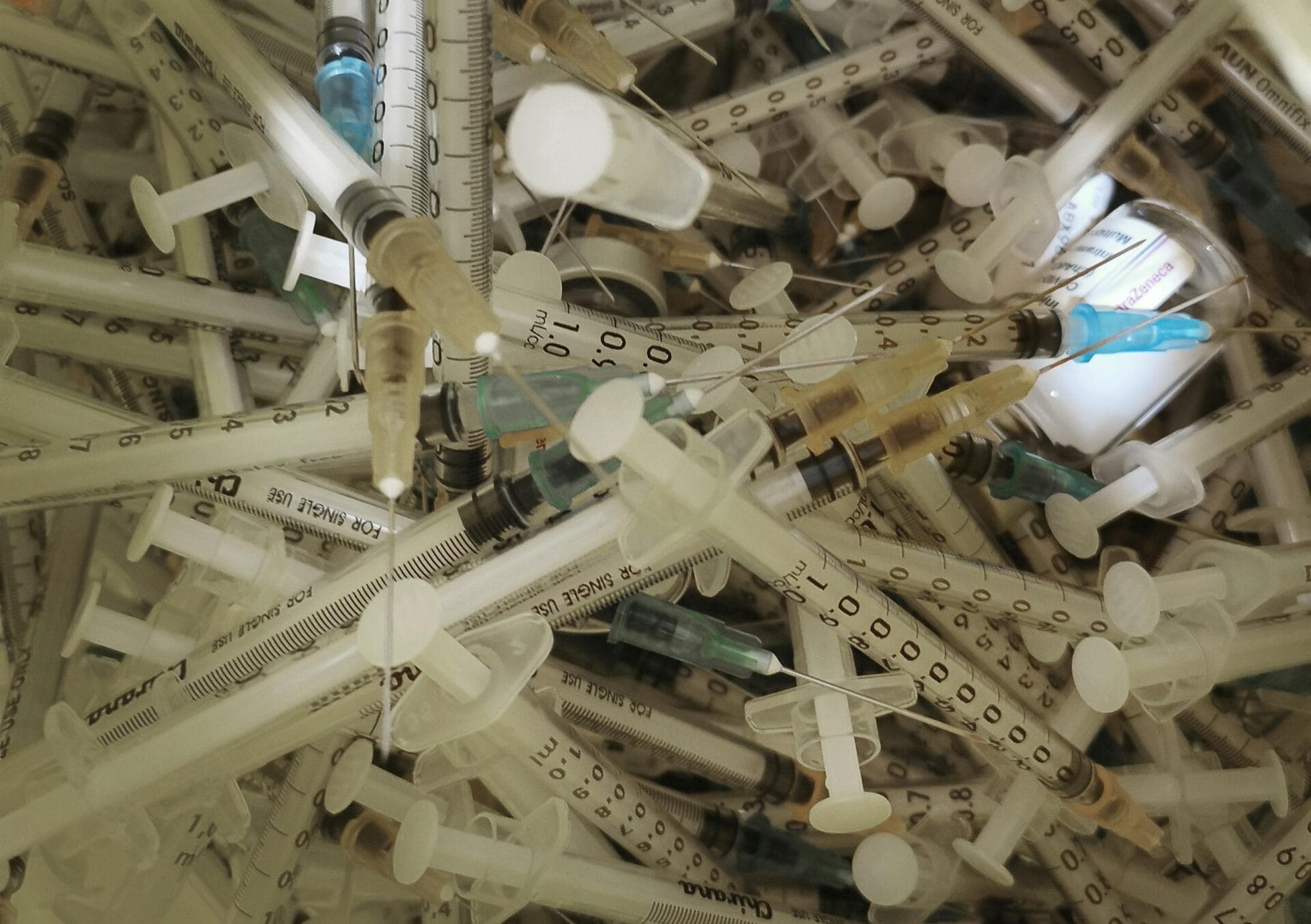 Pile of used medical syringes and needles.