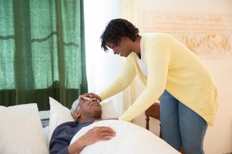 Caregiver assists elderly person in bed.