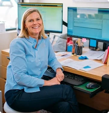 Woman at desk working in office. Medsharps Leadership Team. Mary Jon Hayne
